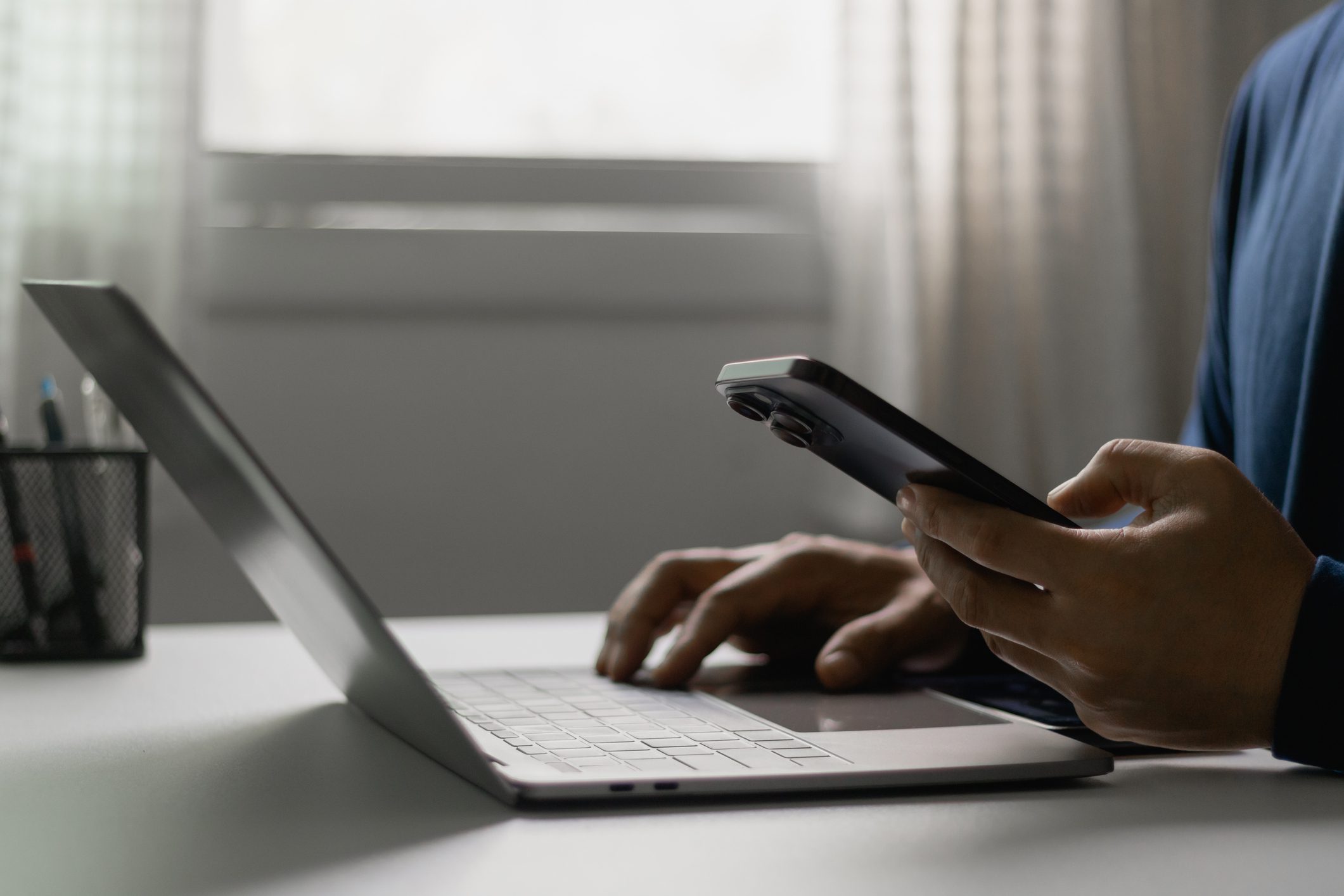 Hands on laptop and holding phone